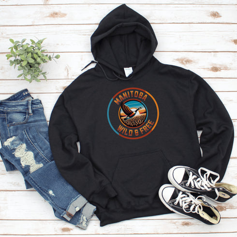 Celebrate the heart of the prairies with our Manitoba – Wild & Free hoodie, featuring a stunning graphic of a Canadian goose soaring over golden wheat fields.